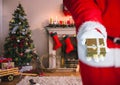 Mid section of santa holding christmas gift in living room Royalty Free Stock Photo