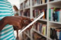 Mid section of schoolboy using digital tablet in library Royalty Free Stock Photo