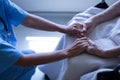 Senior female patient holding hands of surgeon in hospital corridor