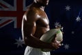 Mid section of shirtless man with trophy and rugby ball against Australian flag