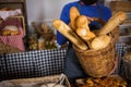 Mid section of staff holding wicker basket of french breads at counter