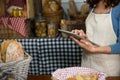 Mid-section of staff using digital tablet at bakery counter