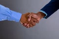 Mid section of two businessmen shaking hands against grey background