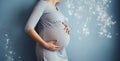 Mid-section of unrecognizable pregnant woman smiling and holding her big belly caringly against blue wall of childrens room. Royalty Free Stock Photo