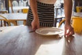 Mid section of waiter arranging plate on table