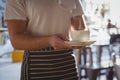 Mid section of waiter holding coffee cup