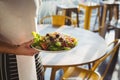 Mid section of waiter holding plate with salad