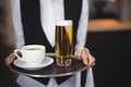 Mid-section of waitress holding tray with coffee and beer glass Royalty Free Stock Photo