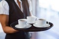 Mid section of waitress holding a tray of coffee cups