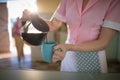 Waitress pouring black coffee in mug at restaurant