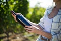 Mid section woman holding wine bottle at vineyard