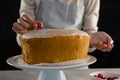 Woman toping a fresh baked cake with cherry