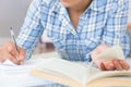 Mid section of young female student doing assignments while lying on the floor