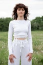 Mid shot attractive yoga instructor girl. Young sports woman in white sportswear on nature background. Calm female