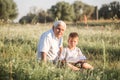 Mid shot of grandfather and his grandson while reading a book together in meadow Small boy making first steps in read