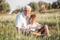 Mid shot of grandfather and his grandson while reading a book together in meadow Small boy making first steps in read