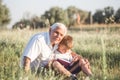 Mid shot of grandfather and his grandson while reading a book together in meadow Small boy making first steps in read