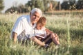 Mid shot of grandfather and his grandson while reading a book together in meadow Small boy making first steps in read