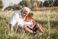 Mid shot of grandfather and his grandson while reading a book together in meadow Small boy making first steps in read