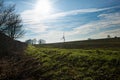 Ploughed fields in winter, with distant wind turbine and dew drenched grass in foreground Royalty Free Stock Photo