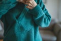midaction, person pulling on a teal sweater, uncluttered environment Royalty Free Stock Photo