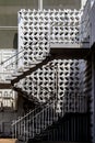 MIdcentry metal stairs on outside of building with decorative concrete behind - alsmost monochromatic with shadows and sun Royalty Free Stock Photo