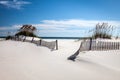 Midday photo of a dune fence with white sand, sea oats at Pensacola Beach, Florida