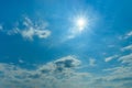 The midday sun shines brightly high in the blue sky. Azure sky with small white clouds on a sunny day. Natural background for