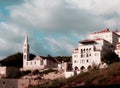 Midday urban view of a church and an interesting architecture house with four floors, balconies and arches, under a cloudy sky Royalty Free Stock Photo