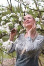 middel aged woman stands in the park next to a flowering tree, Spring time