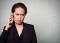 Middle adult Asian woman holding smart phone in angry and boring