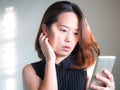 Middle adult Asian woman using smart phone. Action of thinking a