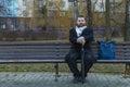 Middle adult calm bearded man sitting on bench lonely melancholy mood in autumn park dray ordinary day