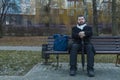 Middle adult calm bearded man sitting on bench lonely melancholy mood in autumn park dray ordinary day