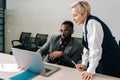 Middle-adult female Caucasian mentor supervisor help male african intern explain computer work corporate software Royalty Free Stock Photo