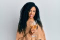 Middle age african american woman drinking a glass of white wine looking positive and happy standing and smiling with a confident Royalty Free Stock Photo