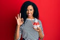 Middle age african american woman eating strawberry ice cream doing ok sign with fingers, smiling friendly gesturing excellent Royalty Free Stock Photo