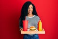 Middle age african american woman eating a tasty classic burger smiling looking to the side and staring away thinking Royalty Free Stock Photo