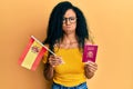 Middle age african american woman holding spain flag and passport puffing cheeks with funny face