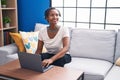 Middle age african american woman using laptop sitting on sofa at home Royalty Free Stock Photo