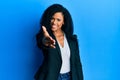 Middle age african american woman wearing business clothes smiling friendly offering handshake as greeting and welcoming Royalty Free Stock Photo