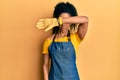 Middle age african american woman wearing professional apron covering eyes with arm, looking serious and sad Royalty Free Stock Photo