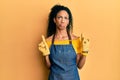 Middle age african american woman wearing professional apron pointing up looking sad and upset, indicating direction with fingers,