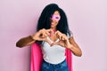 Middle age african american woman wearing super hero costume smiling in love doing heart symbol shape with hands