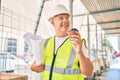 Middle age architect man holding blueprints and drinking take away coffee at the city Royalty Free Stock Photo