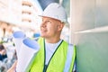 Middle age architect man holding blueprints leaning on the wall at the city Royalty Free Stock Photo