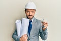 Middle age architect man wearing safety helmet holding blueprints and new home key relaxed with serious expression on face Royalty Free Stock Photo