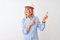 Middle age architect woman wearing glasses and helmet over isolated white background smiling and looking at the camera pointing Royalty Free Stock Photo