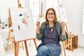 Middle age artist woman at art studio excited for success with arms raised and eyes closed celebrating victory smiling Royalty Free Stock Photo
