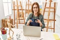 Middle age artist woman smiling happy having video call using laptop at art studio Royalty Free Stock Photo